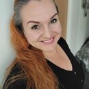 Na fotografii není žádný hudební nástroj ani příslušenství. Je zde zobrazen portrét usmívající se ženy s červenými vlasy v černém oblečení.