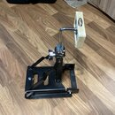 Černý basový pedál z kovu s bílým beaterem. Na beateru je viditelný nápis "REMO PRODUCTS". Povrch pedálu vykazuje mírné známky používání.