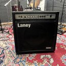 Černý kytarový kombo zesilovač s kovovým ovládacím panelem a černou textilní maskou reproduktoru. Na přední straně je bílý nápis Laney a v pravém dol…