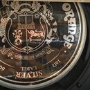 Detailní pohled na zadní kryt reproduktoru. Na kovovém povrchu je nápis ORADGE zopakovaný dvakrát, uprostřed je grafický znak s různými symboly a náp…