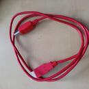 Červený propojovací kabel s USB konektorem na jednom konci a bílým konektorem na druhém. Na červeném plastovém krytu u bílého konektoru je vyražen ná…