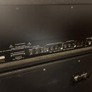 Záběr na zadní panel černého elektronického zařízení s řadou konektorů a přepínačů. Na panelu jsou nápisy CAUTION!, DO NOT OPEN! RISK OF ELECTRIC SHO…