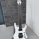 Bílá elektrická kytara s černým hmatníkem a černými plastovými díly. Na hlavě je čitelné logo Jackson. Nástroj má dva humbuckery, tremolo most a dvě…
