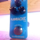Modrý efekt pedál s nápisy FLASHBACK MINI, TRUE BYPASS a tc electronic. Na horní části jsou tři černé oválné ovládací knoflíky a malý přepínač. Povrc…