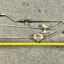Tři kovové chromované tremolo páky pro elektrickou kytaru s černými plastovými koncovkami. Páky mají různý tvar a délku, jedna z nich je rovná bez oh…