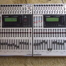 Dvě stříbrné digitální mixážní konzole značky BEHRINGER, model DDX3216. Každé zařízení má v horní části řadu konektorů, centrální displej s nápisem D…