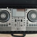 Stříbrný DJ kontrolér Numark MIXSTREAM PRO GO v černém přenosném pouzdře. Zařízení má dva jog-wheels, centrální displej a řadu tlačítek a posuvníků.…