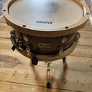 Hnědý buben s dřevěnými obručemi. Na blaně je nápis EVANS HD DRY a na korpusu štítek s textem S.L.A. SONIC LAB PROJECT ZYALIS. Nástroj je osazen chro…