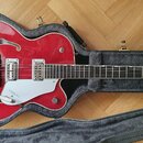 Červená polodublová elektrická kytara v černém tvrdém kufru. Na hmatníku a těle jsou viditelné nápisy GRETSCH a TENNESSEE ROSE. Nástroj má chromované…