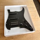 Černý plastový pickguard pro elektrickou kytaru s třemi snímači typu single-coil. Na povrchu jsou u ovládacích knoflí bílé nápisy VOLUME, TONE a TONE…