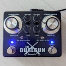 Černý kytarový efekt s nápisem THE DUALGUN a logem Demonfx. Zařízení má šest ovládacích knoflíků s popisky HEAVY-HAND, VOLUME, VOLUME, STRING-SINGER,…