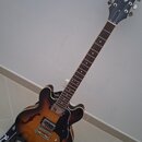 Elektrická kytara s polodupatým korpusem v barevném přechodu od žluté k tmavě hnědé. Na hlavě hmatníku je bílý nápis Epiphone a logo s listem. Kytara…