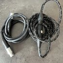Na fotografii jsou dva svité kabely. Levý kabel je černý s kovovými konektory, na jeho povrchu je čitelně nápis "Dygiso". Pravý kabel má černý textil…