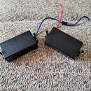 Dvě černé obdélníkové krabičky s dráty, pravděpodobně snímače nebo elektronické komponenty. Z krabiček vedou modré a červené vodiče, které jsou v jed…