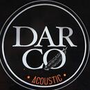 Detailní záběr na kulaté logo s bílým nápisem DAR CO a oranžovým nápisem ACOUSTIC na černém pozadí. Mezi písmeny C a O je umístěn obrázek pírka. Logo…