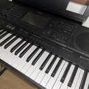 Černý digitální klavír značky YAMAHA, model PSR-SX700. Nástroj má bílé a černé klávesy, ovládací panel s displejem, několika tlačítky a voličem. Povr…