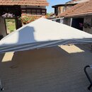 Fotografie zobrazuje rozložený stříšek v šedé barvě s kovovou konstrukcí. Střecha je z textilního materiálu, který vykazuje mírné vrásnění. Na plátně…