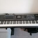 Šedý digitální klavír s černými a bílými klávesami. Na pravé straně je bílý nápis KURZWEIL PC4. Horní panel obsahuje displej, několik posuvníků, tlač…