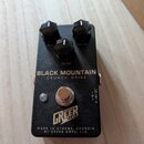 Černý kytarový efekt s nápisy BLACK MOUNTAIN a CRUNCH DRIVE. Na horní části jsou tři černé ovládací knoflíky s popisky VOL, TONE a GAIN. Ve spodní čá…