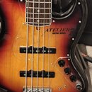 Elektrická basová kytara s tělem v červeno-žlutém sunburst provedení a hnědým hmatníkem. Na průhledném pickguardu je nápis ATELIER GUITAR WORKS s log…