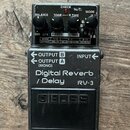 Šedý efekt pedál značky BOSS, model RV-3 Digital Reverb / Delay. Na horní části jsou čtyři černé ovládací knoflíky s popisky BALANCE, TONE, R.TIME a…