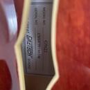 Detailní záběr na štítek uvnitř hudebního nástroje. Na štítku je uveden nápis MODEL NO. G5622 a SERIAL NO. CYGCC20100238. V dolní části je logo GRETS…