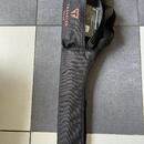 Černý textilní obal na kytaru s popruhem a zipovou kapsou. Na horní části je červeným písmem nápis TRAVELER GUITAR a vedle něj červené logo ve tvaru…