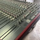 Míchací pult s šedým horním panelem a červeným bočním rámem. Na pravé straně je bílý nápis ALLEN & HEATH a modelové označení ZED 24. Povrch pultu obs…