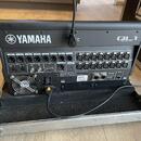 Zadní strana černé digitální mixážní konzole s nápisem YAMAHA a označením modelu QL1 DIGITAL MIXING CONSOLE. Zařízení obsahuje řadu vstupů a výstupů,…