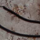 Černý spirálový instrumentální kabel s konektory na obou koncích. Jeden konektor je zakončen bílým plastovým prstencem, druhý má černou krytku. Kabel…