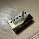 Fotografie zobrazuje kytarový snímač typu humbucker s chromovaným krytem. Kryt je hladký, zrcadlový a obsahuje šest otvorů pro póly. Na povrchu nejso…