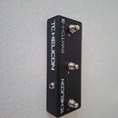 Černý obdélníkový nožní spínač s třemi kovovými tlačítky. Na povrchu jsou bílé nápisy TCHELICON, SWITCH-3 a u tlačítek čísla 1, 2 a 3. Povrch je v do…