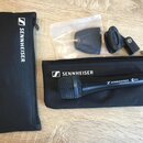 Černý dynamický mikrofon s nápisem SENNHEISER MADE IN GERMANY a označením e935. Součástí je černý textilní pouzdro s bílým logem SENNHEISER, držák mi…