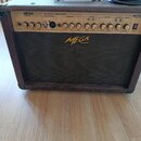 Černý akustický kombozesilovač s nápisem MEGATONE ACOUSTIC AMPLIFIER a logem MEGA AMP na přední mřížce. Horní ovládací panel obsahuje několik potenci…
