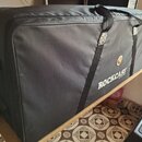 Černý polstrovatý pouzdro na hudební nástroj z textiledního materiálu. Na boku je bílý nápis ROCKCASE a nad ním malé kulaté logo. Pouzdro má dvě čern…