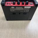 Zadní strana černého kompaktního basového komba. Na zadním panelu je bílý štítek s nápisy VOX, MODEL: AC2 RV-BASS a sériovým číslem 005475. Jsou zde…