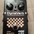 Černý efekt pedál s nápisy DynaVerb a High Dynamics Stereo Reverb. V horní části jsou dva černé otočné ovladače s popisky REVERB a TONE a přepínač TY…