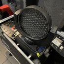 Černý LED reflektor typu moving head umístěný v transportním kufru. Na spodní části přístroje je digitální displej a ovládací prvky, vedle kterých je…