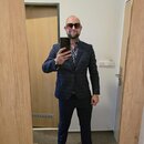 Na fotografii není žádný hudební nástroj ani příslušenství. Je zde zobrazen muž v tmavém kostýmu, slunečních brýlích a s mobilním telefonem v ruce.