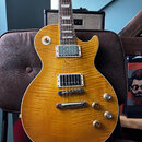 Elektrická kytara s žlutým plamenovitým javorovým topem a bílým lemováním. Nástroj má dva humbuckery s kovovými kryty, Tune-o-matic můstek a čtyři ov…