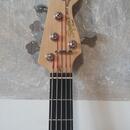 Hlava a hmatník basové kytary z přírodního světlého dřeva s černým hmatníkem. Na hlavě je nápis Squier JAZZ BASS by Fender. Nástroj má čtyři chromova…