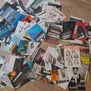 Fotografie zobrazuje hromadu rozházených papírových manuálů, návodů a časopisů k hudebním nástrojům. Jsou zde viditelné loga a názvy značek KORG, Rol…