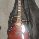 Akustická kytara s cutawayem v červenohnědém sunburst provedení, umístěná v černém softcasu. Na hlavě hmatníku je bílý nápis „Dreadnought“. Uprostřed…