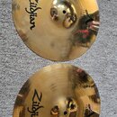 Dvě mosazné činely značky Zildjian z řady Custom. Na obou jsou viditelné nápisy Zildjian a Custom. Povrch činelů je Injuries s viditelnými kladivovým…