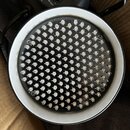 Fotografie zachycuje detail svítidla s kulatým polem drobných bílých LED diod na černém podkladu, umístěných v bílém kruhovém rámu. V horní části je…