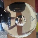 Zlatavý kovový činel s vyznačeným okrajem. Na povrchu je černý nápis Zildjian a logo A s textem CUSTOM 20th Anniversary Ride MEDIUM Thin 22". Povrch…