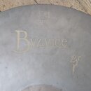 Detailní pohled na povrch činchy v matné, šedé barvě s viditelným broušením. Uprostřed je zlatý nápis Byzance a pod ním text 18" Sand Thin Crash. V h…