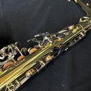 Detailní záběr na zlatý lakovaný saxofon z kovového materiálu. Jsou vidět klapy, mechanismus a černé polstrování pod klapami. Povrch je lesklý, bez v…