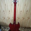 Zadní pohled na červenou elektrickou kytaru s tmavě červeným průsvitem. Na hlavě jsou vidět čtyři ladicí mechanismy z každé strany a nápis "Gibson".…