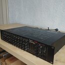 Černý 12kanálový mixážní pult s nápisy Roland M-12E a 12CHANNEL MIXER. Horní kryt obsahuje schéma s názvem M-12E BLOCK DIAGRAM. Zařízení vykazuje mír…